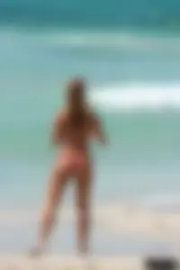 Topless girl in a tiny thong on the beach playing paddle ball