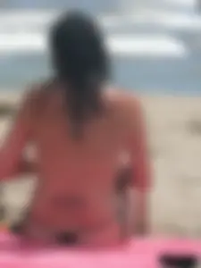 Brunette lady topless and in a black thong on the beach