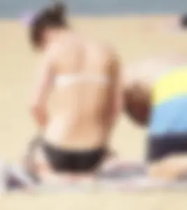 Sexy girl on the beach laying out and bending over in her bikini
