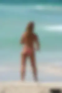 Topless girl in a tiny thong on the beach playing paddle ball