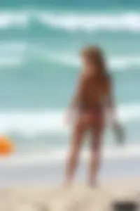 Topless girl in a tiny thong on the beach playing paddle ball