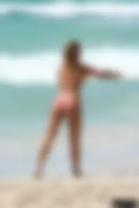 Topless girl in a tiny thong on the beach playing paddle ball
