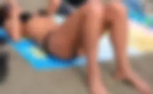 Lady in black bikini showing some pubes while laying out