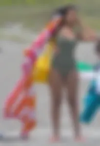 Hot candid brunette chick with a sexy body in a green one piece swimsuit at the beach