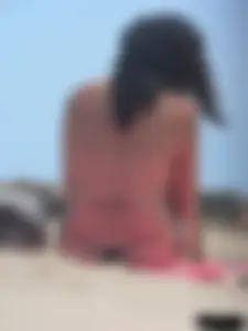 Brunette lady topless and in a black thong on the beach