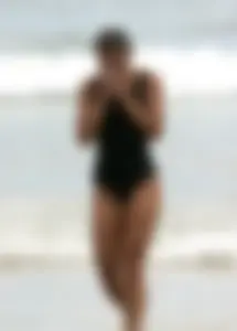 Skinny sexy lady on the beach in a black swimsuit