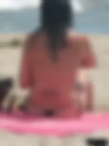 Brunette lady topless and in a black thong on the beach