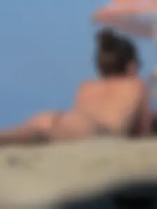 Sexy babe with a nice body topless and in a thong on the beach