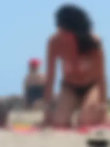 Brunette lady topless and in a black thong on the beach