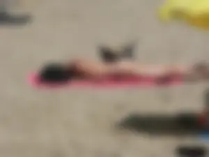 Brunette lady topless and in a black thong on the beach