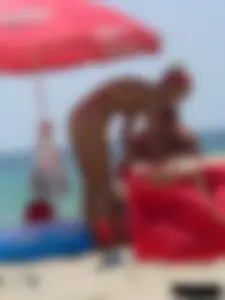 Topless skinny blonde lady in a g-string bikini at the beach
