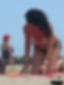Brunette lady topless and in a black thong on the beach