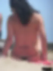 Brunette lady topless and in a black thong on the beach