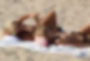 Topless mom and daughter on the beach getting some sun