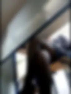 College girl's crossed legs in black pantyhose and a skirt seen from under desk in classroom