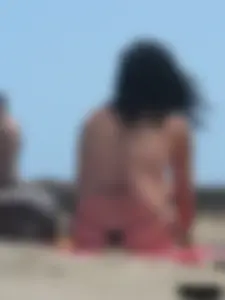 Brunette lady topless and in a black thong on the beach