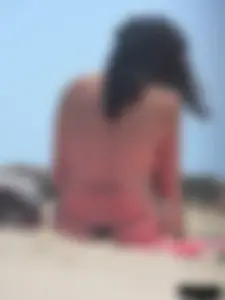 Brunette lady topless and in a black thong on the beach