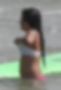 Brunette bikini girl on the beach and surfing in her bikini