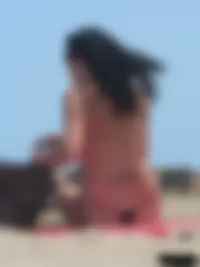 Brunette lady topless and in a black thong on the beach