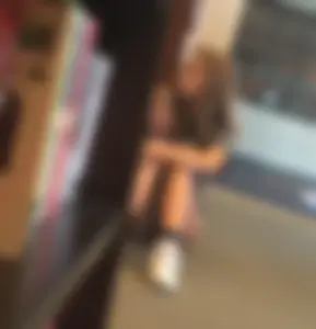 Cute skinny teen in shorts sitting on the floor at the book store