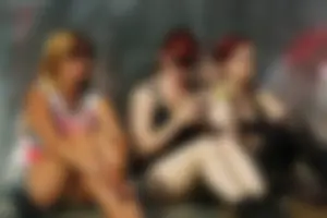 Three girls sitting, one redhead in jeans and a redhead and blonde in shorts