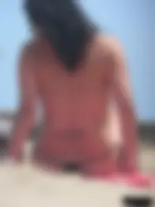 Brunette lady topless and in a black thong on the beach