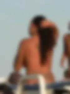 Topless tattooed lady on the beach with fake big tits