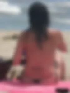 Brunette lady topless and in a black thong on the beach