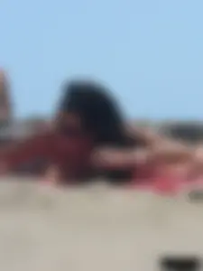 Brunette lady topless and in a black thong on the beach