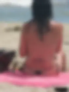 Brunette lady topless and in a black thong on the beach