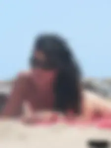Brunette lady topless and in a black thong on the beach