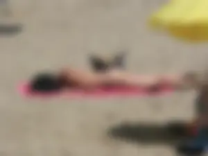 Brunette lady topless and in a black thong on the beach