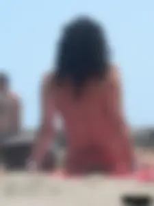 Brunette lady topless and in a black thong on the beach