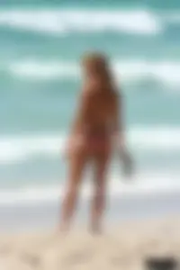 Topless girl in a tiny thong on the beach playing paddle ball