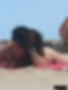Brunette lady topless and in a black thong on the beach