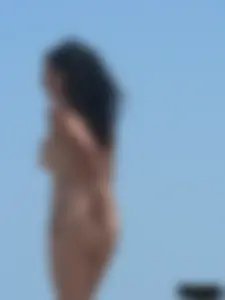 Brunette lady topless and in a black thong on the beach