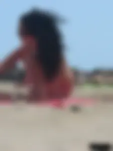 Brunette lady topless and in a black thong on the beach