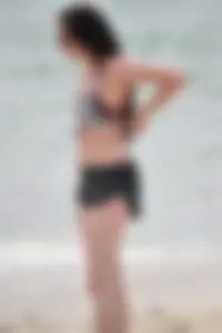 Brunette girl in black shorts and bikini top on the beach
