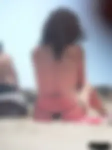 Brunette lady topless and in a black thong on the beach
