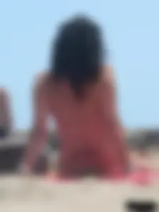 Brunette lady topless and in a black thong on the beach
