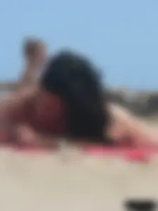 Brunette lady topless and in a black thong on the beach