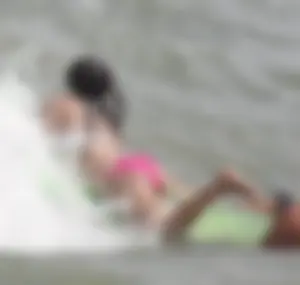 Brunette bikini girl on the beach and surfing in her bikini