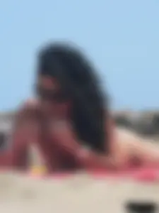 Brunette lady topless and in a black thong on the beach