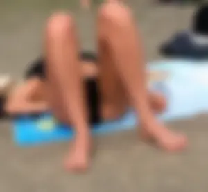 Lady in black bikini showing some pubes while laying out