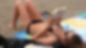Lady in black bikini showing some pubes while laying out