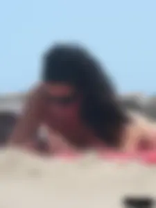 Brunette lady topless and in a black thong on the beach