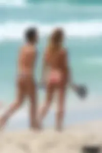 Topless girl in a tiny thong on the beach playing paddle ball