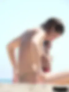Topless beach milf looking sexy in a tiny g-string bikini