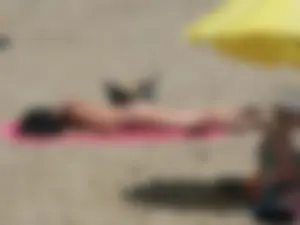 Brunette lady topless and in a black thong on the beach