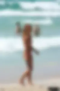 Topless girl in a tiny thong on the beach playing paddle ball